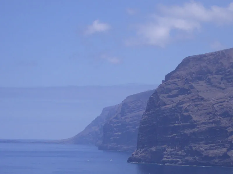 The sheer walls of the Acantilados de los Gigantes above the ocean, shrouded in haze