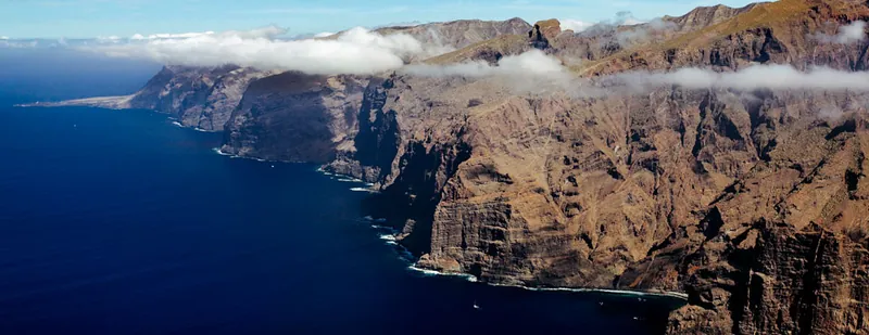 Aerial view of the Acantilados de los Gigantes cliffs plunging into the ocean, with low cloud