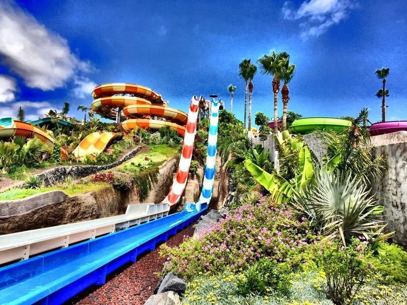 Colourful spiral water slides among palm trees and flowers at Aqualand Costa Adeje