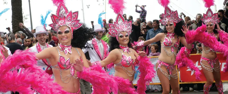 Dancers in pink costumes with feathers and sparkling headdresses parading at the Tenerife Carnival