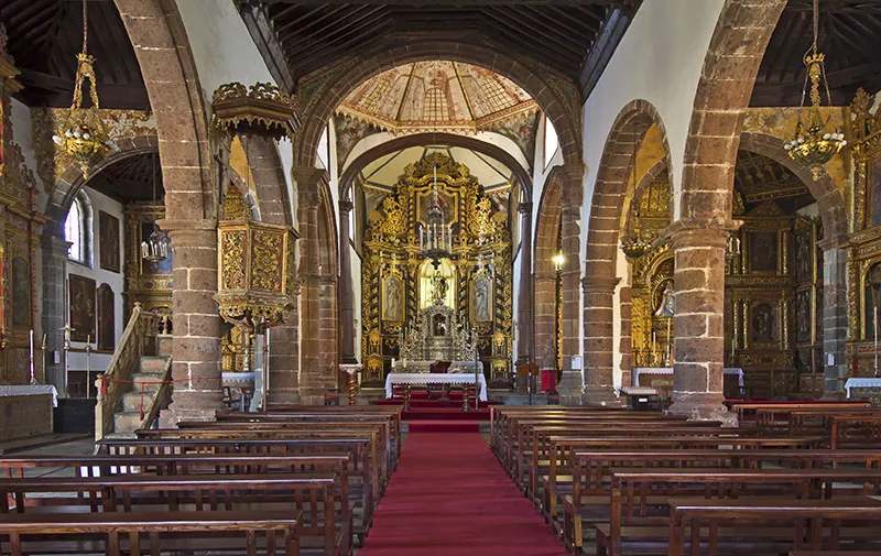 Inside the Church of Santa Catalina in Tacoronte: arched naves, pews and a gilded altar