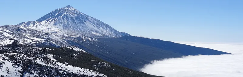 Snow-capped Mount Teide above a sea of clouds under Tenerife’s blue sky