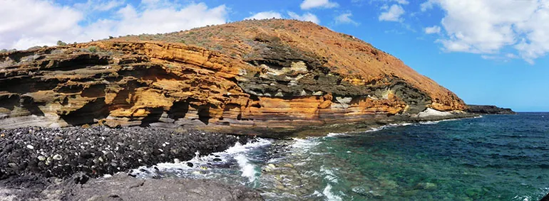 The layered yellow rocks of Montaña Amarilla by the turquoise sea of Costa del Silencio