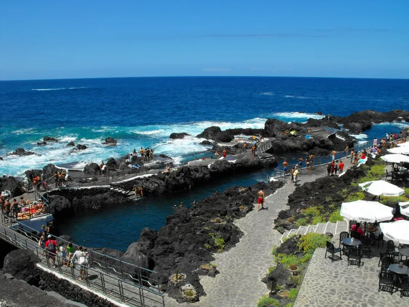 The natural pools of El Caletón in Garachico among lava rocks, with bathers and parasols