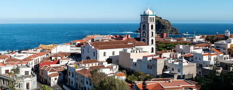 Garachico’s red roofs and white bell tower, with the Roque islet and the ocean behind