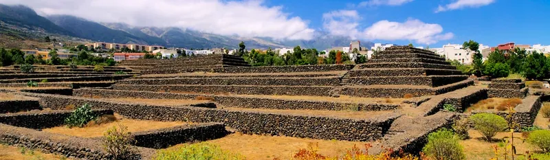Panoramic view of the stepped pyramids of Güímar, with mountains and clouds in the background