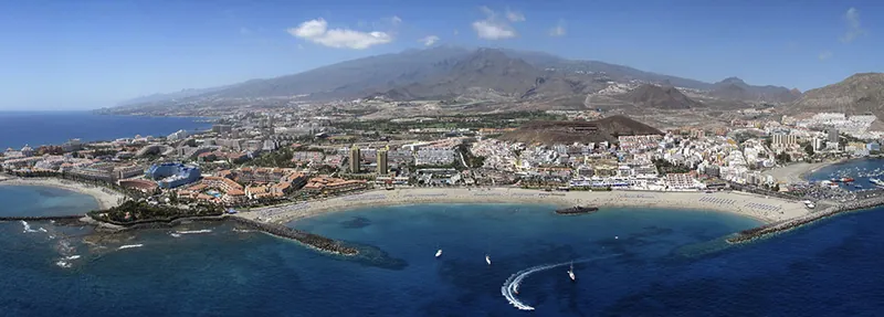 Aerial view of Los Cristianos bay, with its beach, harbour and the mountains of southern Tenerife