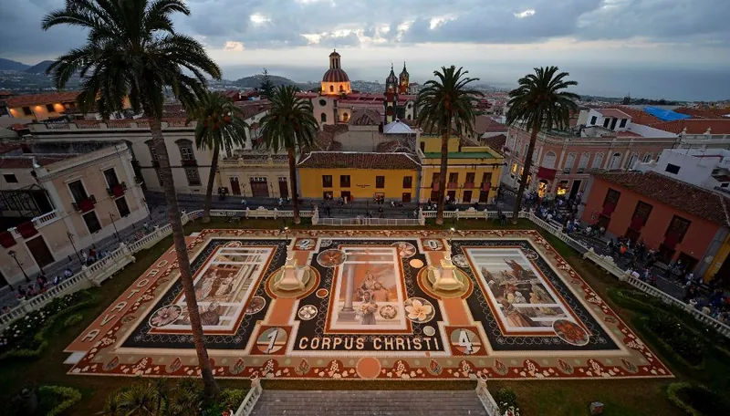 Artistic Corpus Christi carpet in the square at La Orotava, among palms and historic buildings