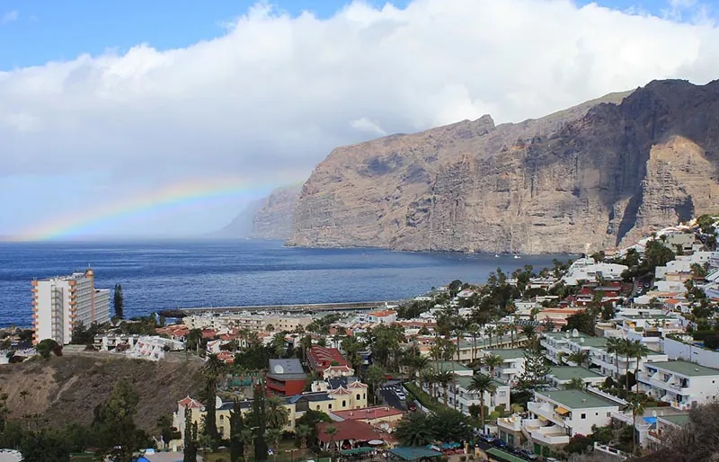 Seafront houses in Los Gigantes, with the towering cliffs and a rainbow in the background
