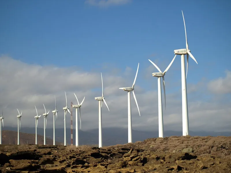 A row of white wind turbines on rocky ground at the Granadilla Wind Farm