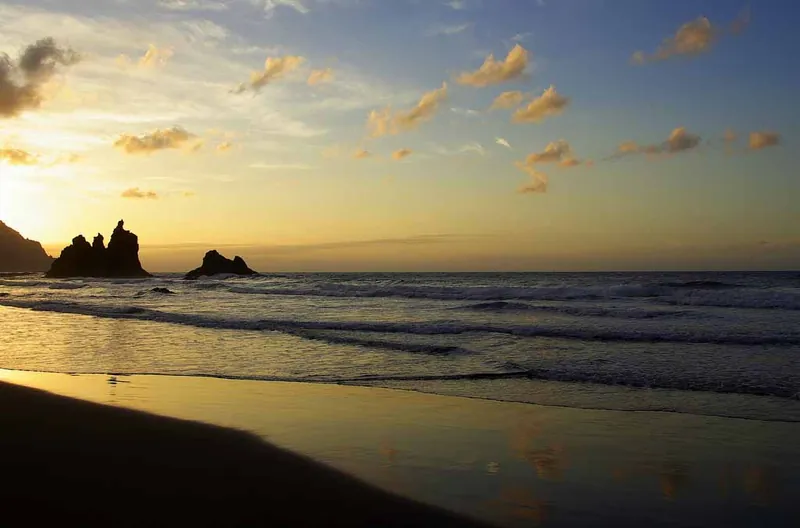 Golden sunset at Playa Benijo, with silhouetted sea stacks and wet sand