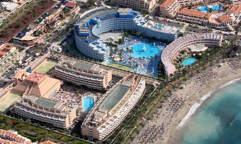 Aerial view of large hotel complexes with pools beside the beach at Playa de las Américas