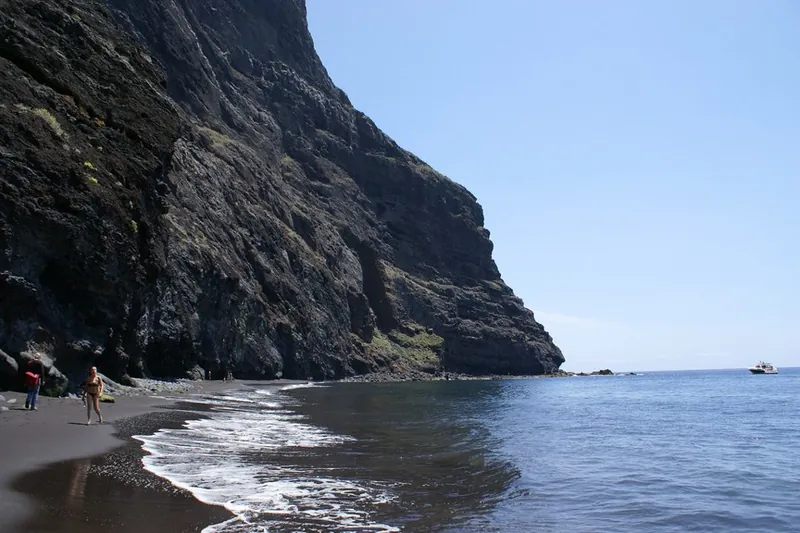 Black sand and waves at Playa de Masca beneath towering rock walls