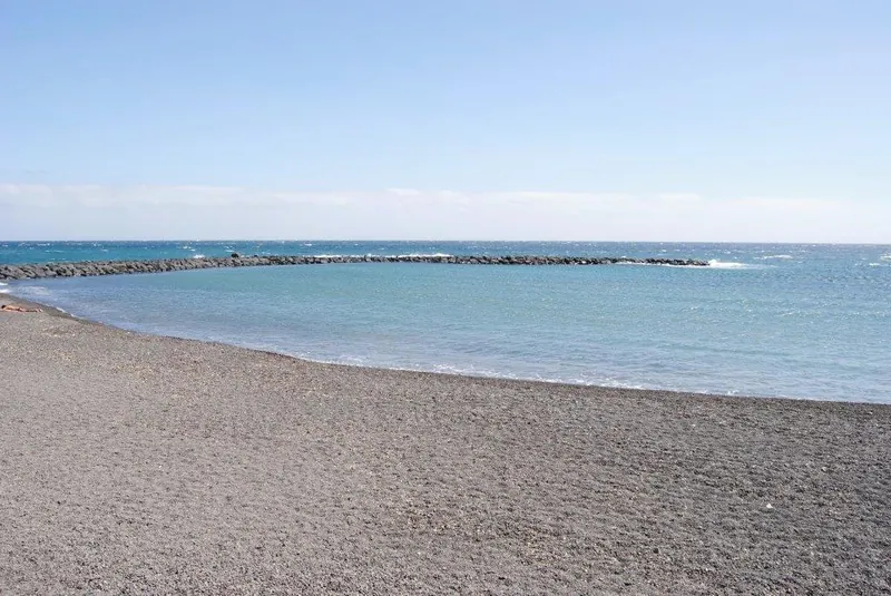 Dark shingle and calm water sheltered by the breakwater at Playa del Cabezo, Puertito de Güímar