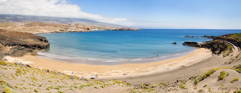 Panoramic view of the golden-sand bay of Playa Grande between dunes and rocks