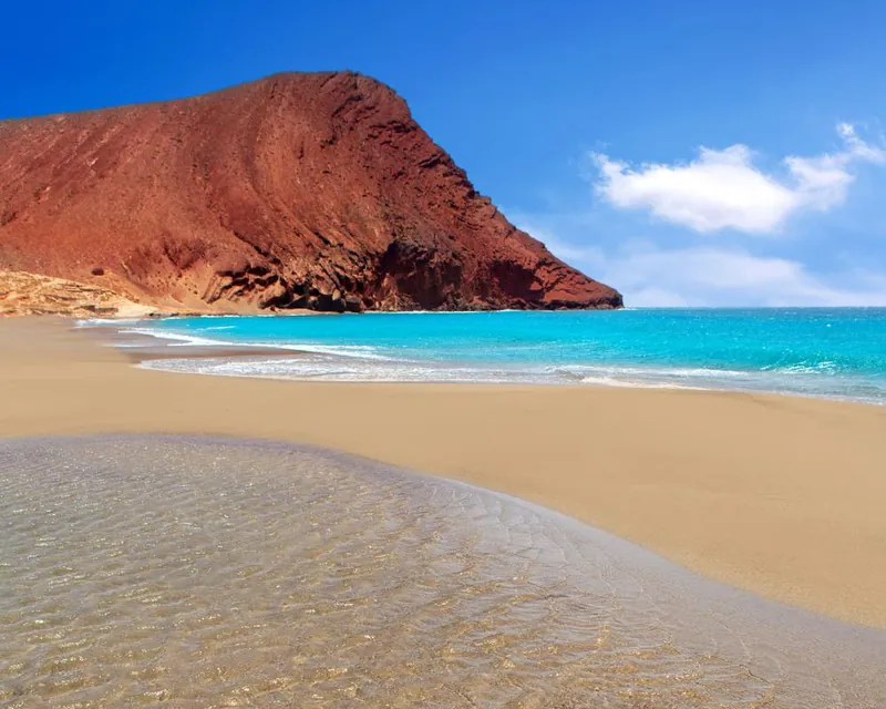 Golden sand and turquoise water of Playa La Tejita at the foot of Montaña Roja
