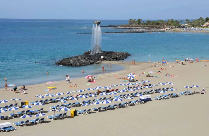Rows of blue-and-white parasols and the fountain on the rock at Playa Las Vistas