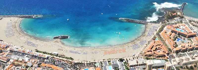 Aerial view of the crescent bay of Playa Las Vistas with turquoise water and breakwaters