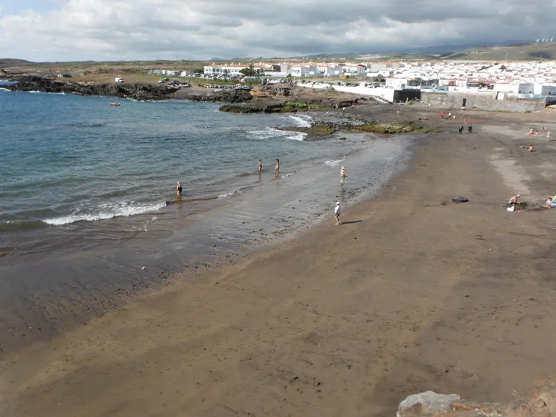 The shoreline of Playa Los Abriguitos with bathers and the white houses of Abades behind