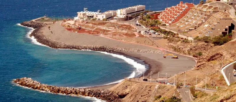 Playa de la Nea from above during construction, with breakwaters, a digger and residential complexes