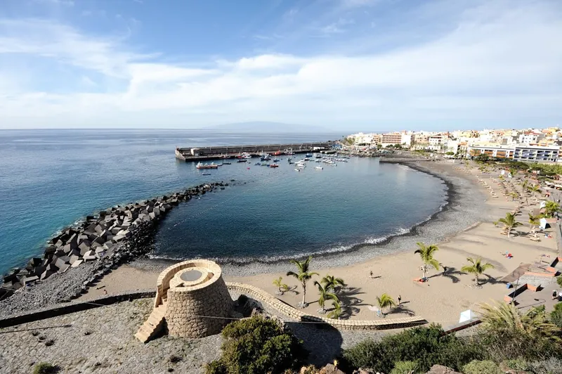 The bay at Playa San Juan: breakwater, small harbour, palms and La Gomera on the horizon