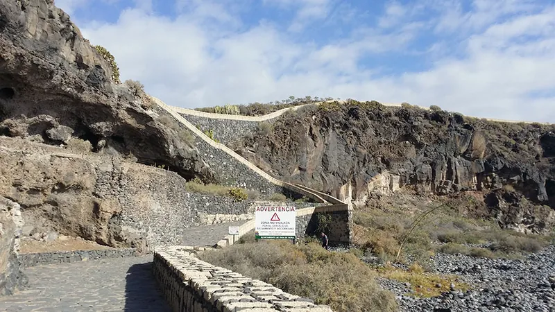 The cobbled path along the rocky coast of Playa San Juan, between low stone walls