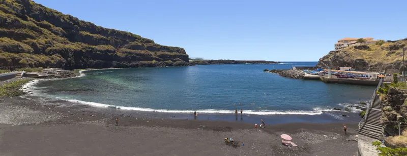 The shell-shaped bay of Playa San Marcos with black sand, cliffs and a small harbour