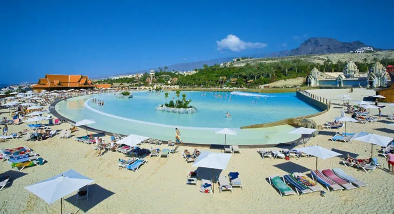 The large pool with a white-sand beach, parasols and sunbeds at Siam Park