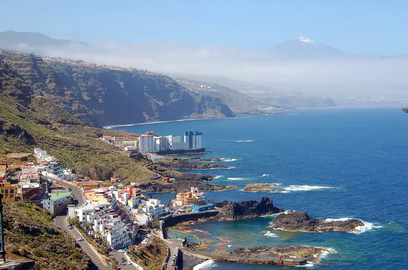 The Tacoronte coast with white houses, natural pools, cliffs and snow-capped Mount Teide in the background