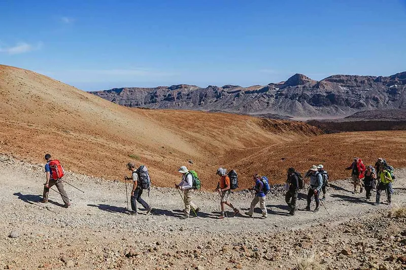 A group of walkers with rucksacks on a path among Tenerife’s volcanic mountains